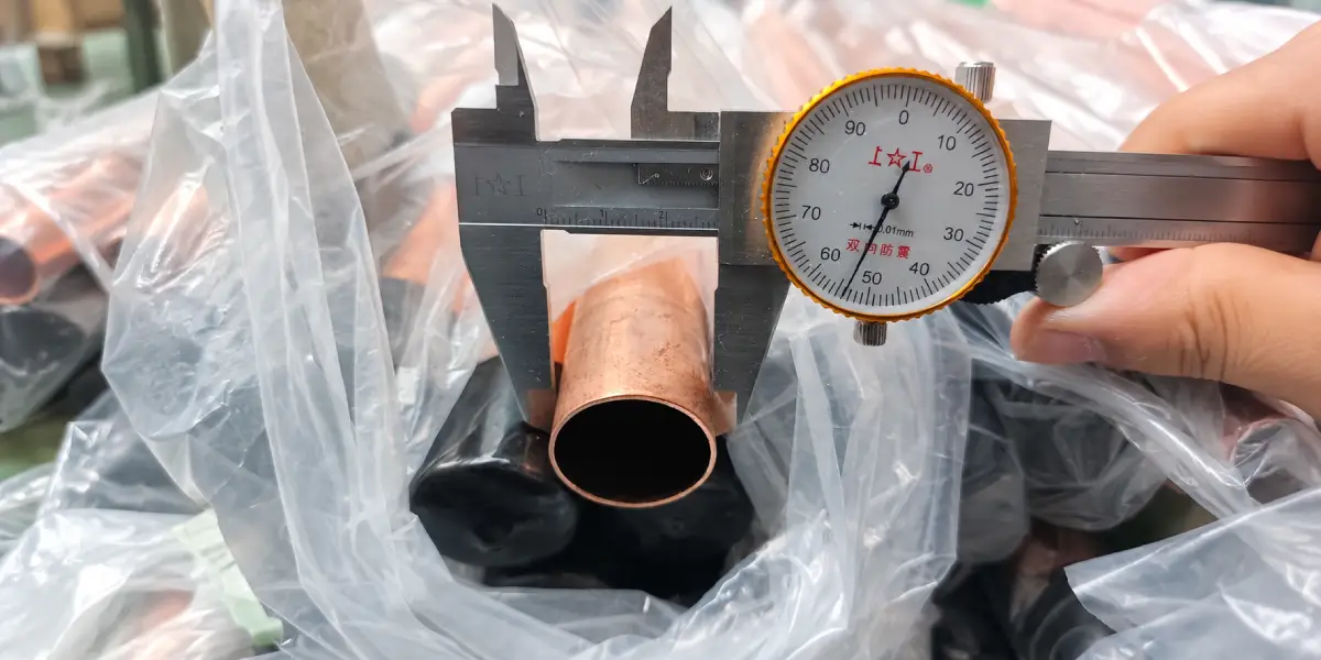 Dial caliper measuring the outside diameter of a copper tube for HVAC and refrigeration use.