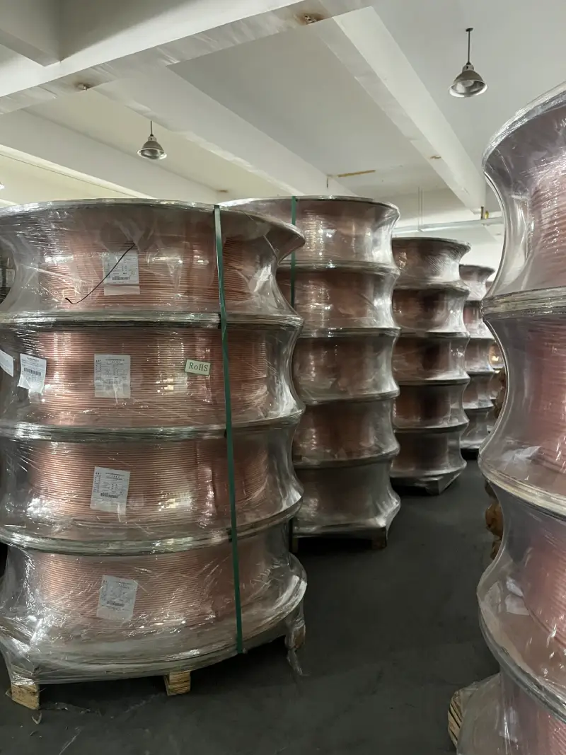 Large wrapped copper coil spools in the raw material warehouse of a copper tube factory
